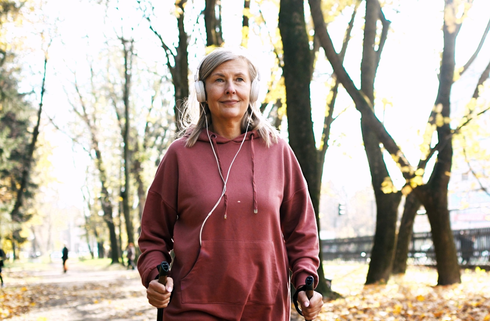 A senior woman listening to an audiobook while on a walk outdoors.