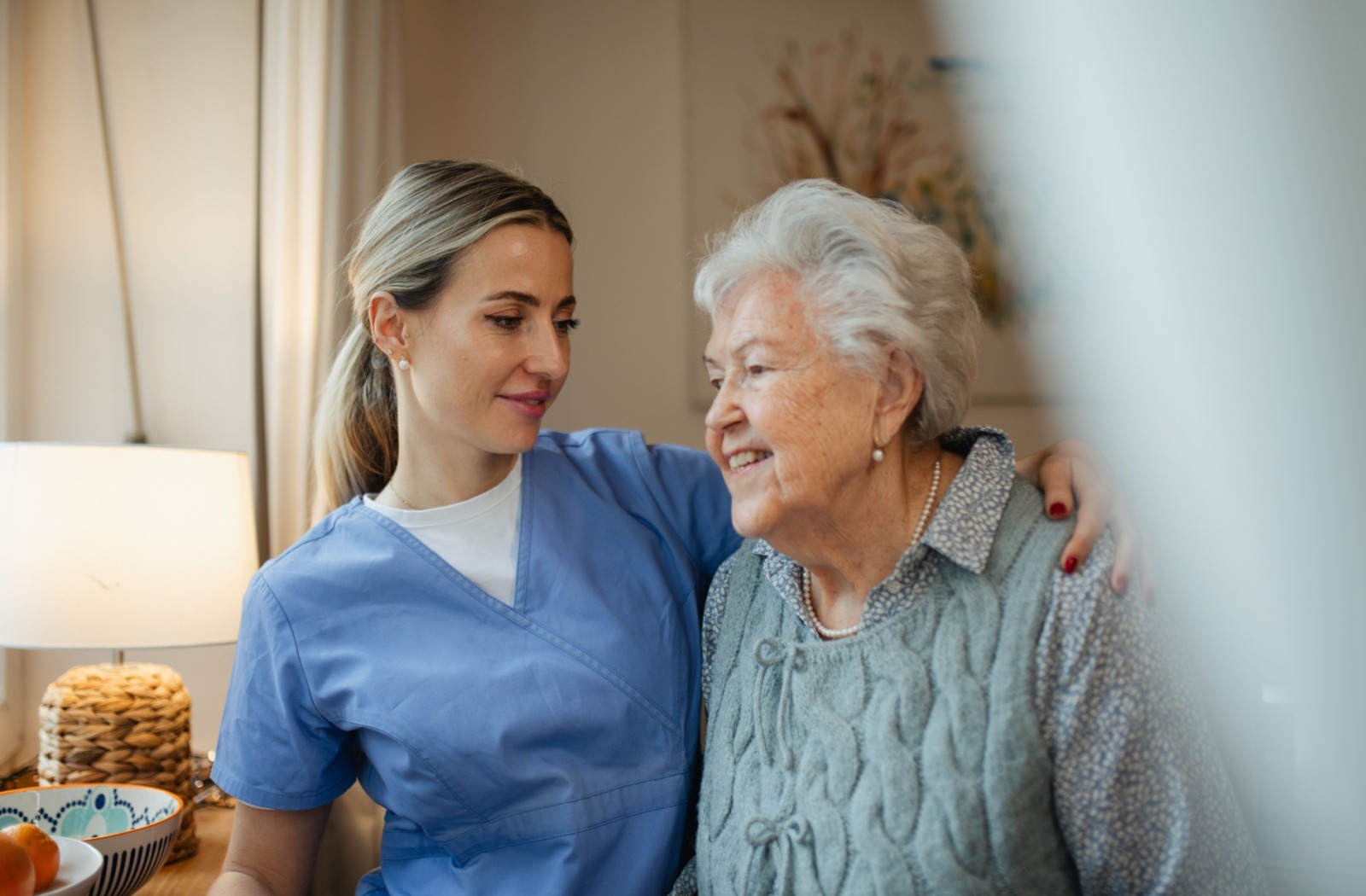 An assisted living caregiver embraces a senior resident in their community apartment.

