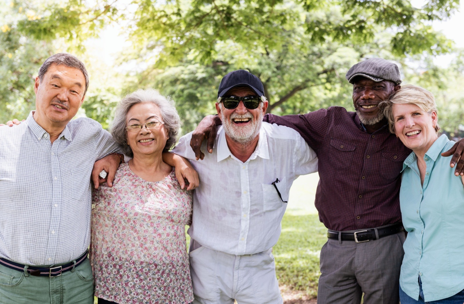 A group of senior friends who met at a senior living community embrace each other while smiling for the camera.
