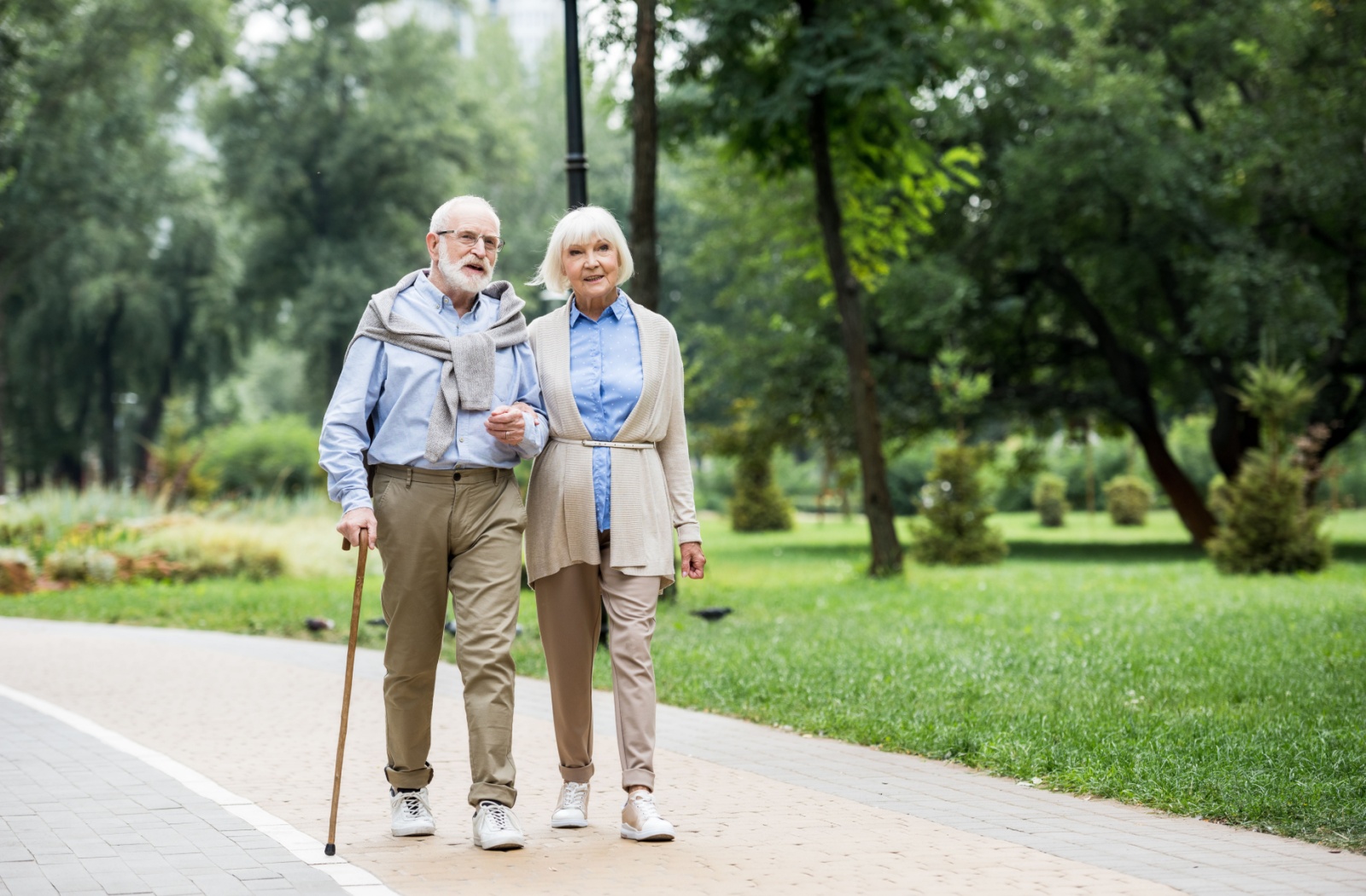 A senior couple enjoys a relaxing stroll in a park during springtime.