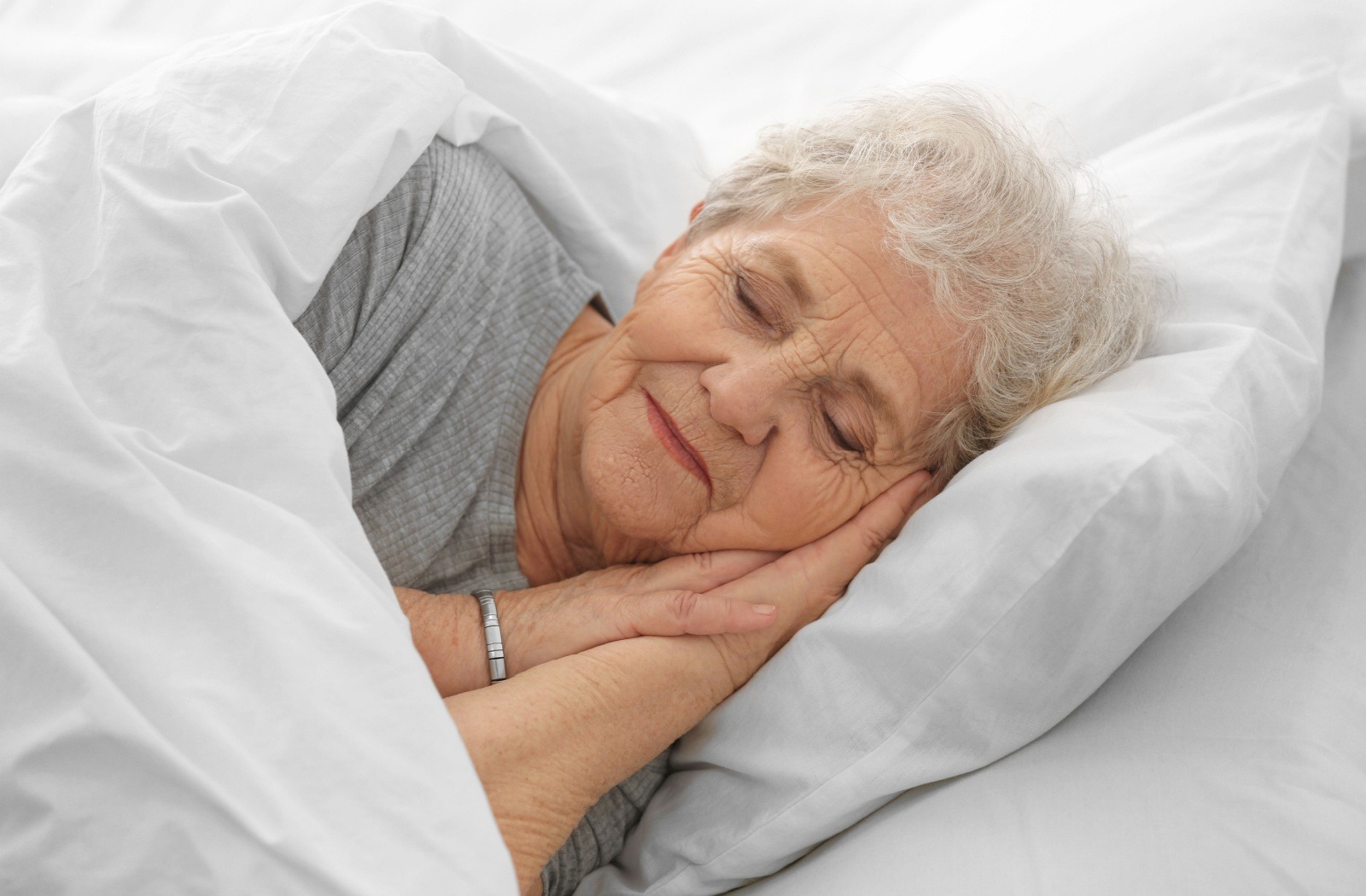 A senior has a restful sleep in bed in their senior living community apartment.
